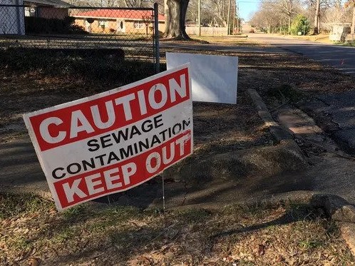 Sign in yard reading "Caution sewage contamination keep out"