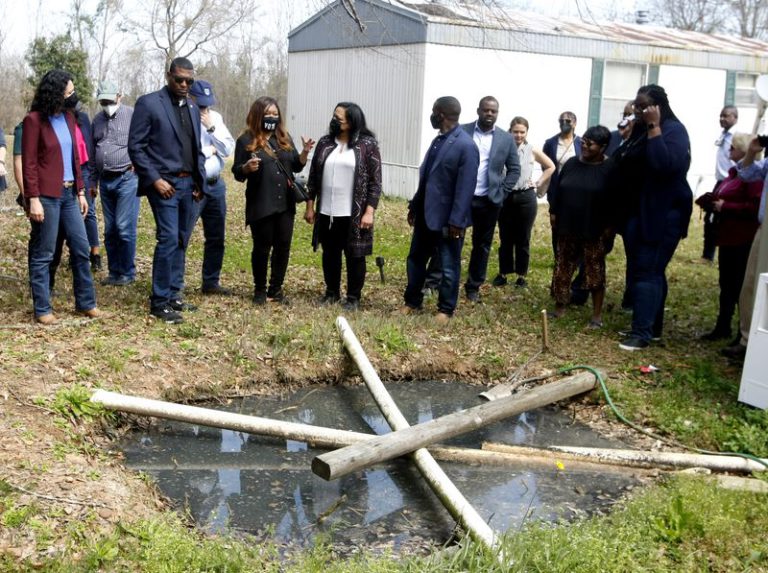 Group of people looking over raw sewage in the ground from a straight pipe