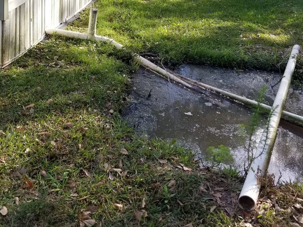 Straight pipe pouring raw sewage from a trailer onto the ground